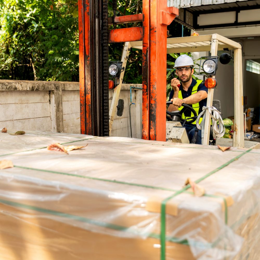 Man worker at forklift driver happy working in industry factory logistic ship. Man forklift driver in warehouse area. Forklift driver sitting in vehicle in warehouse.